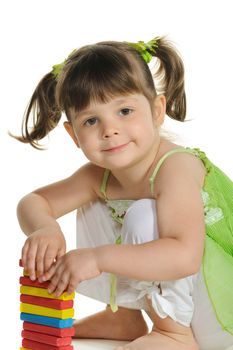 The lovely little girl plays colour wooden cubes. It is isolated on a white background