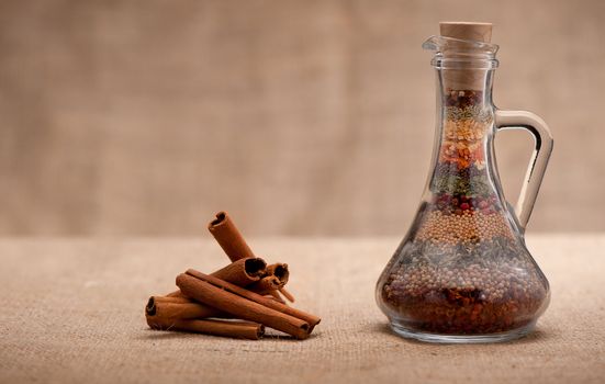 Bottle of spices and cinnamon. Capacity with a set of various spices and cinnamon on a rough background