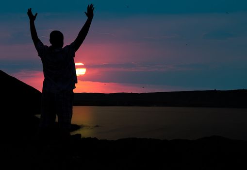 The man welcomes the sunset sun. Upwards the lifted hands