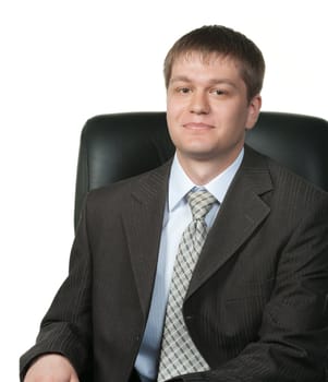 The young businessman in an armchair. It is isolated on a white background