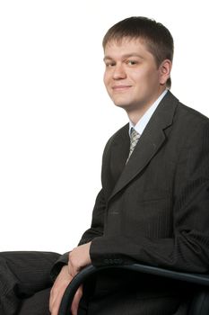 The young businessman in an armchair. It is isolated on a white background