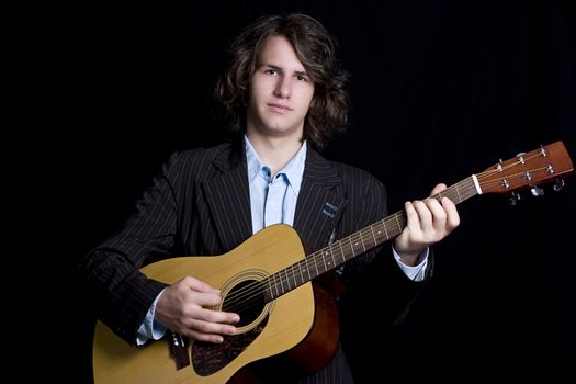 Male teenager folk guitar player with blank expression