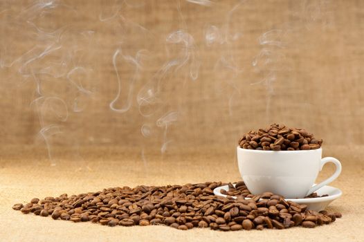 Cup with grains of coffee and a smoke. Grunge background