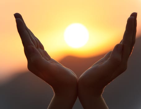 Decline in hands. A sunset on a background of the lifted female hands