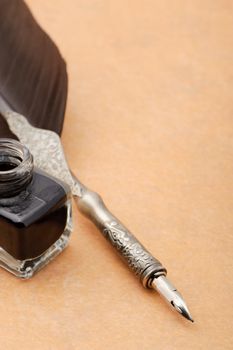 Feather quill and inkwell on an old paper. Photo closeup