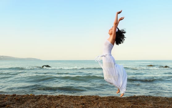 The young woman jumps on seacoast. A picturesque landscape