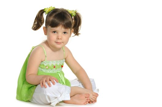 Pretty the little girl sits on the white. It is isolated on a white background