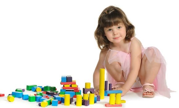 The lovely little girl plays colour wooden cubes. It is isolated on a white background