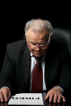 The elderly man in eyeglases reads the document wtih text fired. A photo against a dark background