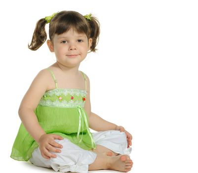 Pretty the little girl sits on the white. It is isolated on a white background