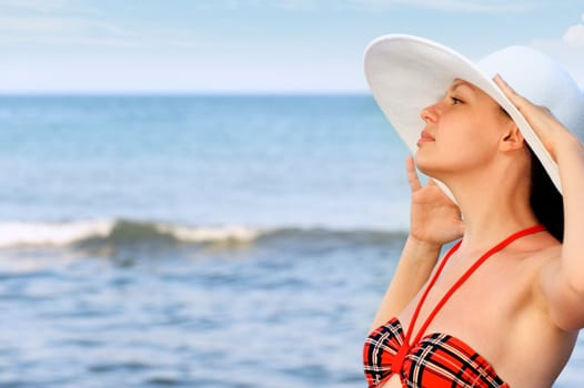 The girl in a hat against the sea and blue sky