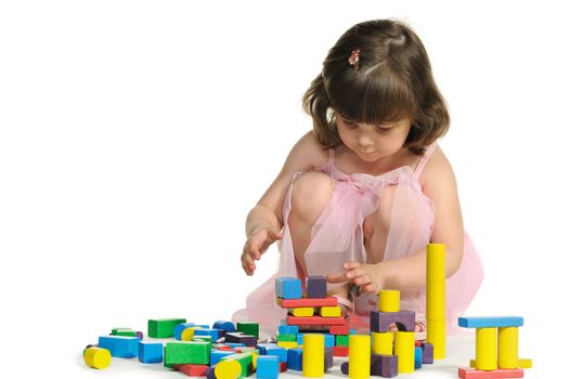The lovely little girl plays colour wooden cubes. It is isolated on a white background