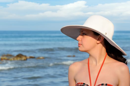 The girl in a hat against the sea and blue sky