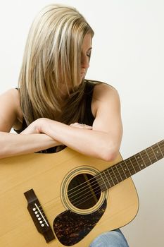 Thirty something women leaning on a accoustical guitar
