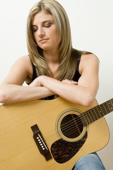 Thirty something women leaning on a accoustical guitar