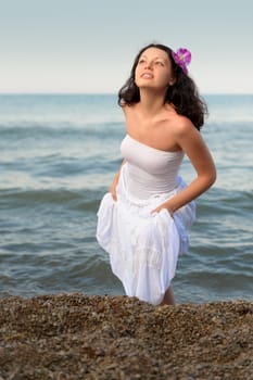 The woman in a white sundress on seacoast. A picturesque landscape