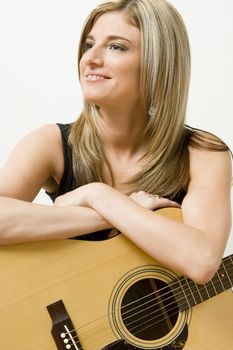 Thirty something women leaning on a accoustical guitar