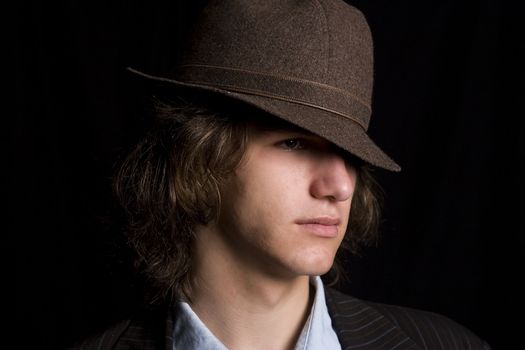 Male teenager wearing a suit and hat with mad expression