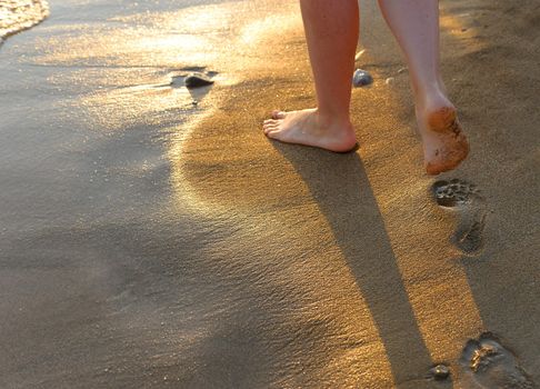 footprint on sand. Sunset illumination, a fragment of female feet