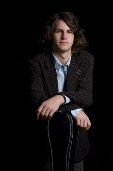  portrait of a male teenager wearing a suit leaning on a instrument case