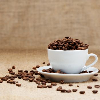 White cup with coffee grains. Grunge background