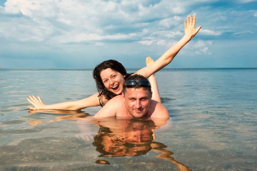 Young pair in the sea. Against the blue sky