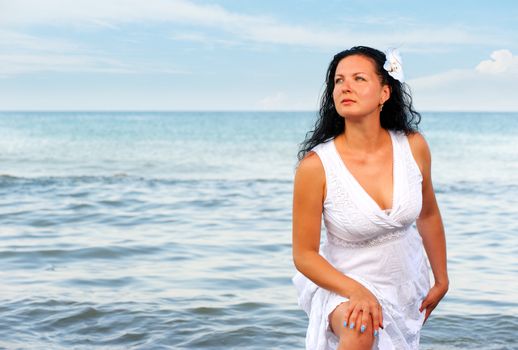 The woman in a white sundress on seacoast. A picturesque landscape