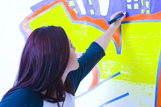 Teen girl drawing a graffiti on a wall