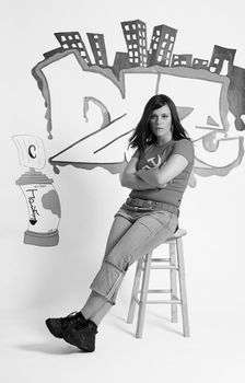 Teen girl sitting on a stool in front of a graffitied wall looking bored out of her skull