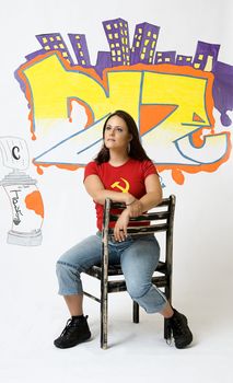 Young women day dreaming sitting on a ruff up chair in front of a graffiti background
