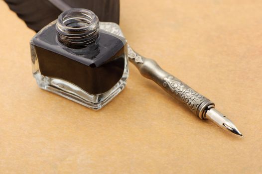 Feather quill and inkwell on an old paper. Photo closeup