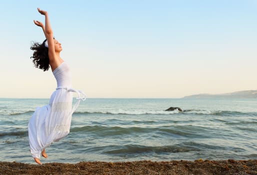 The young woman jumps on seacoast. A picturesque landscape