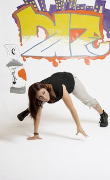 young women in the middle of a breakdancing move balancing on her hands done in front of a graffiti background