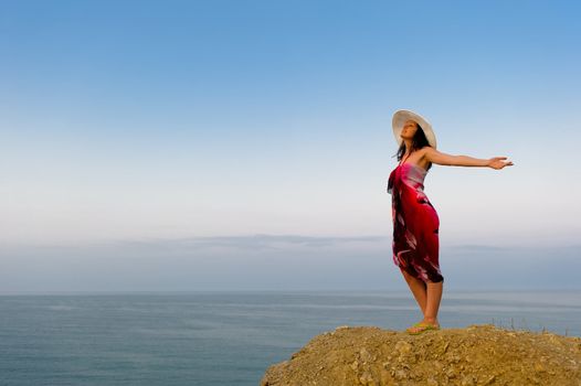 The woman on a mountain with open hands, against the blue sky