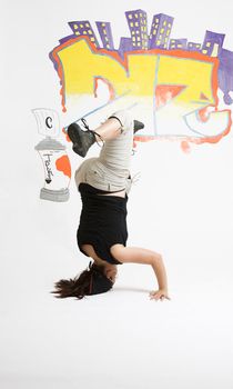 young women in the middle of a breakdancing move balancing on her head done in front of a graffiti background