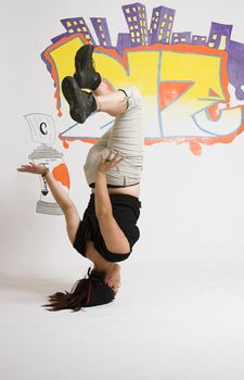 young women in the middle of a breakdancing move balancing on her head done in front of a graffiti background