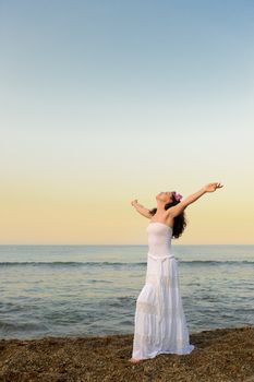 The woman in a white sundress on seacoast with open hands. A picturesque landscape