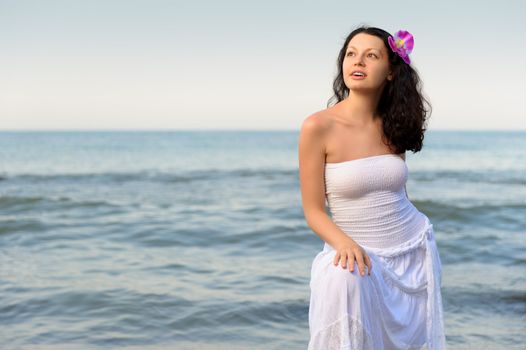 The woman in a white sundress on seacoast. A picturesque landscape