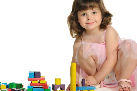 The lovely little girl plays colour wooden cubes. It is isolated on a white background