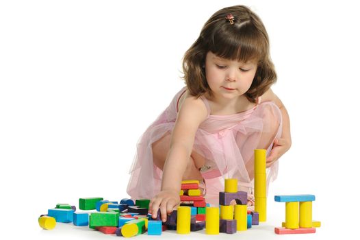 The lovely little girl plays colour wooden cubes. It is isolated on a white background