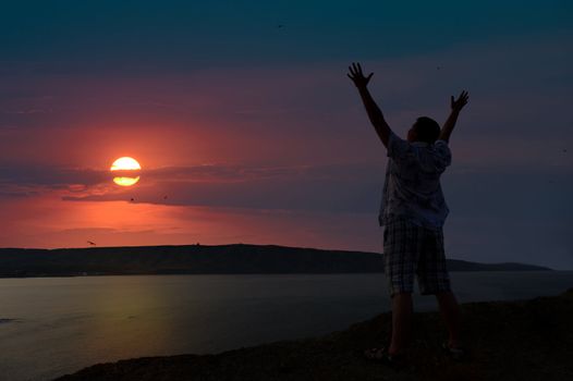 The man welcomes the sunset sun. Upwards the lifted hands