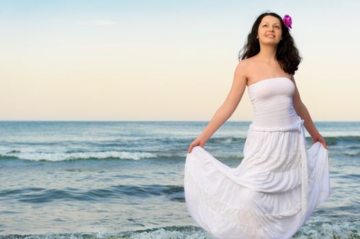 The woman in a white sundress on seacoast. A picturesque landscape