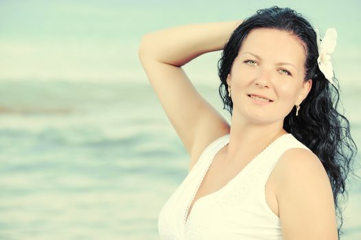 The woman in a white sundress on seacoast. Warm toned image