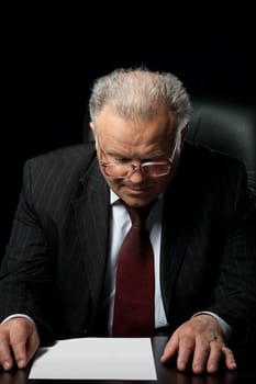 The elderly man in eyeglases reads the empty document. A photo against a dark background