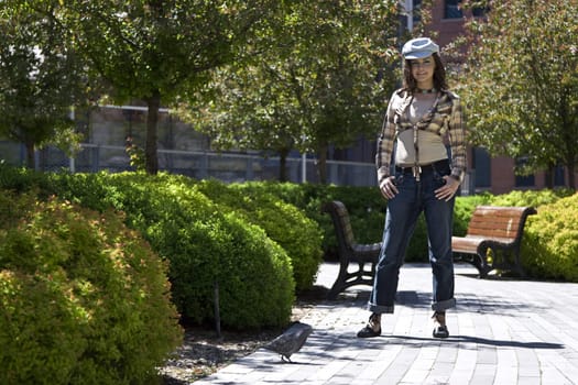 Teen girl stricking a pose in a park in front of a pidgeon