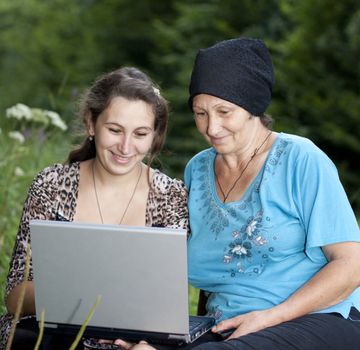 Women with a laptop sitting on green grass