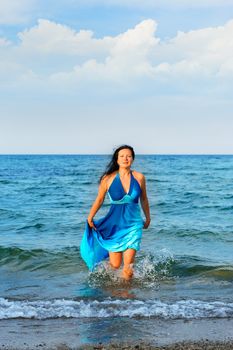 The attractive woman exit the sea. A dark blue dress