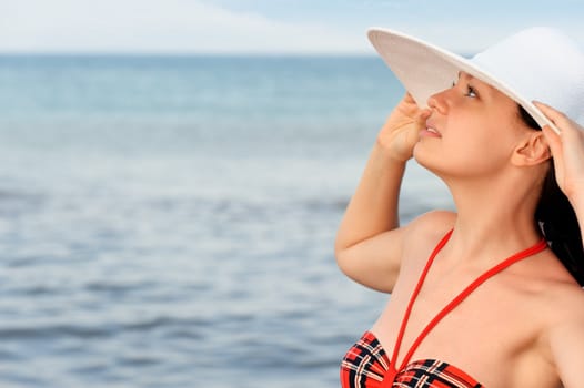 The girl in a hat against the sea and blue sky