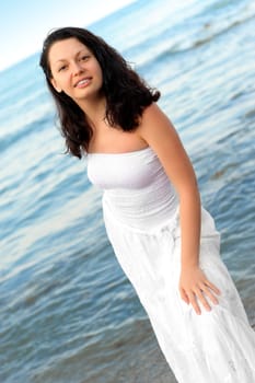 The woman in a white sundress on seacoast. A picturesque landscape