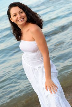 The woman in a white sundress on seacoast. A picturesque landscape